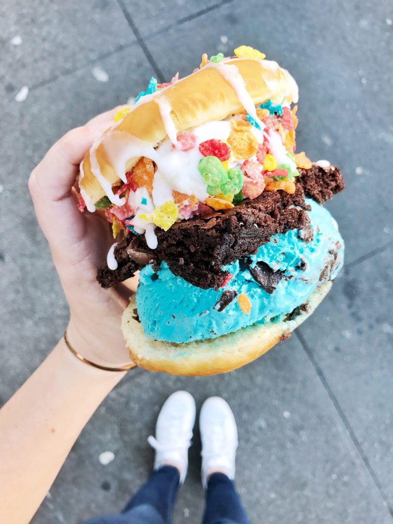 a person holding a doughnut with a variety of toppings.