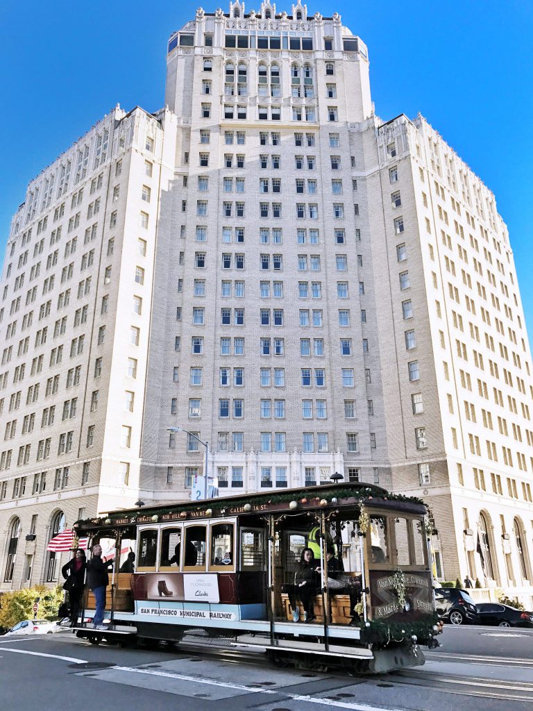 a trolley car on a city street in front of a tall building.