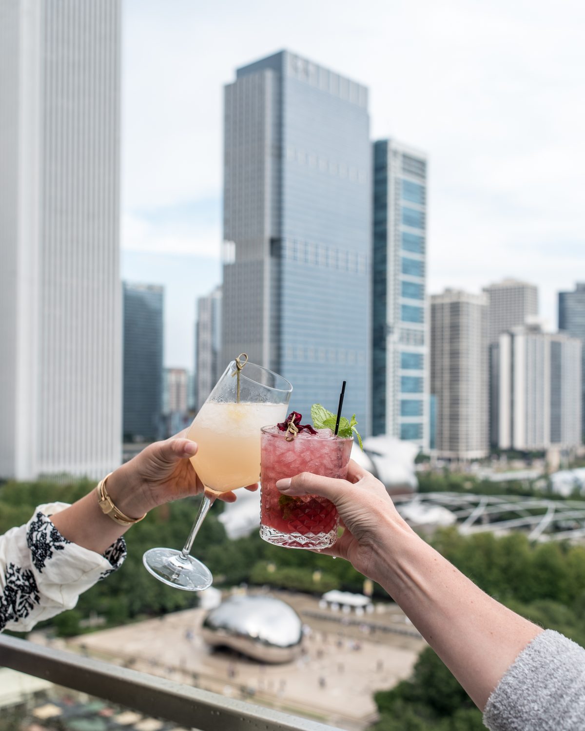 two people toasting with drinks in front of a cityscape.
