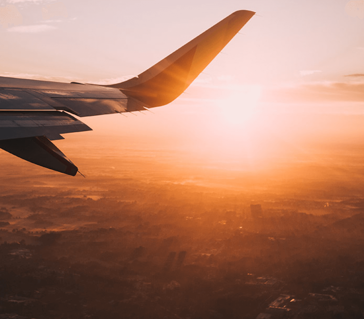 a view of the wing of an airplane as the sun sets.