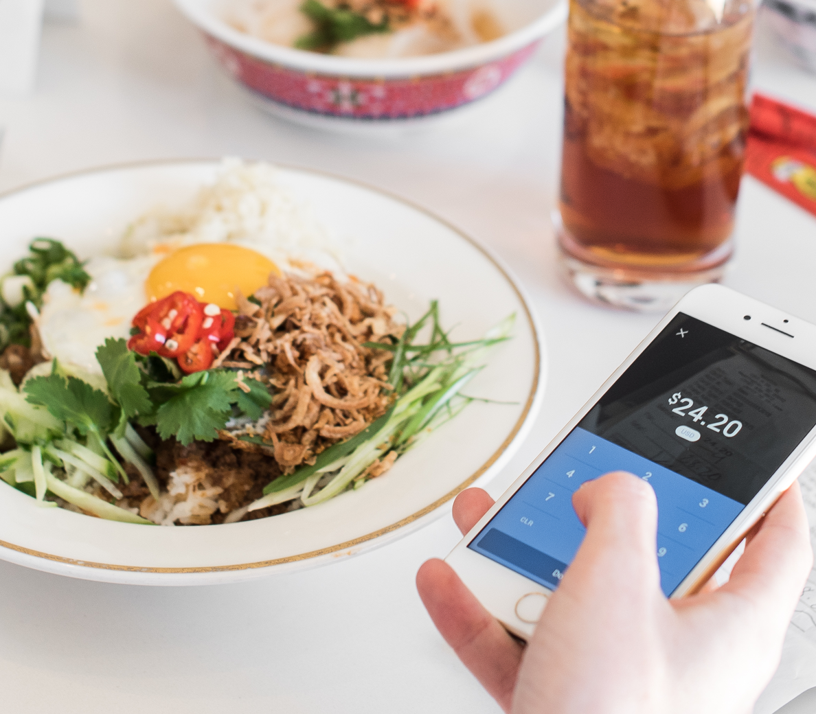 a person holding a smart phone in front of a plate of food.