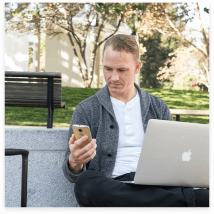 a man sitting on a bench looking at his cell phone.