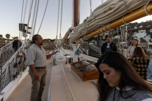 A group of people standing on the deck of a sailboat.