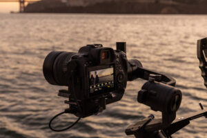 A camera on a tripod next to a body of water.