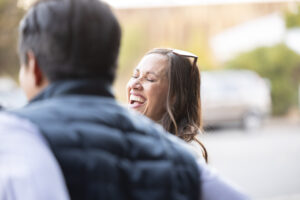A woman laughs while a man is talking to her.