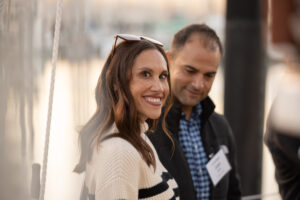 A man and woman smiling while standing on a boat.