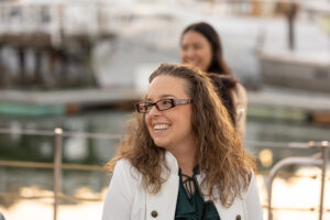 A woman in glasses is smiling while sitting on a boat.
