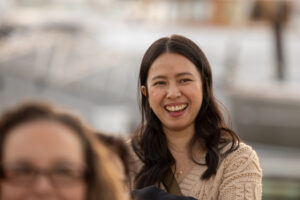 A woman smiles while sitting next to a boat.