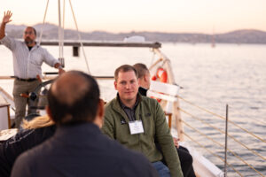 A group of people on a sailboat talking to each other.