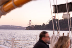 A couple on a boat looking at the golden gate bridge.