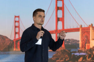 A man is giving a presentation in front of the golden gate bridge.