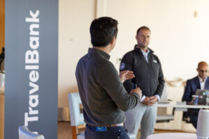 Two men standing in front of a travel bank sign.