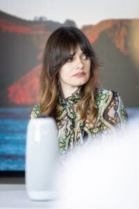 A woman sitting at a table in front of a speaker.