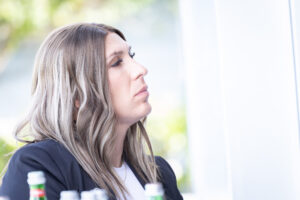 A woman sitting at a table next to a bottle of water.
