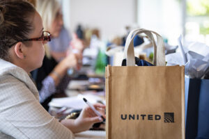 A woman is sitting at a table with a united bag.