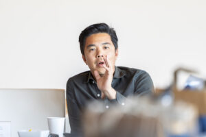 A young asian man sitting at a desk in an office.