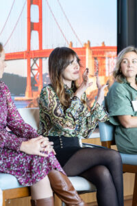 Four women sitting on chairs in front of a golden gate bridge.