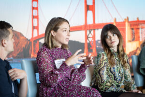 A group of people sitting in front of a golden gate bridge.