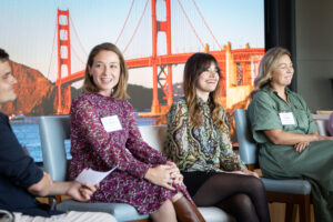 A group of women sitting on chairs in front of a golden gate bridge.