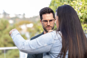 A man with glasses is looking at a woman's phone.