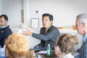 A group of people sitting around a table in a meeting.