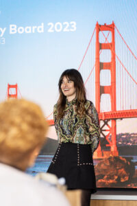 A woman standing in front of a screen.
