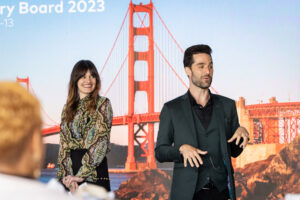 A man and woman standing in front of a golden gate bridge.