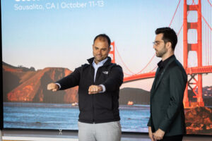 Two men standing in front of a screen with the golden gate bridge in the background.