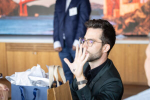 A man is holding a gift bag in front of a group of people.
