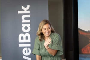 A woman is standing in front of a screen with a travelbank logo.