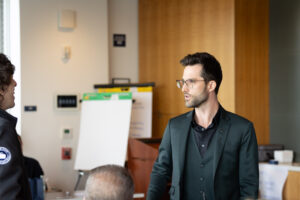 A man in a suit is talking to another man in a conference room.