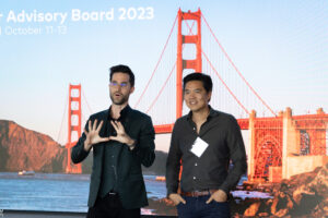 Two men standing in front of a screen.