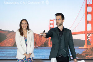 A man and woman standing in front of the golden gate bridge.