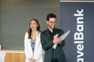 A man and woman standing in front of a travel bank sign.