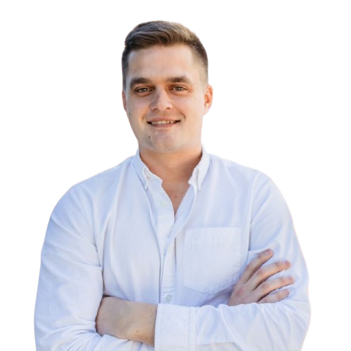 Man in a white shirt with arms crossed, smiling at the camera against a plain background.